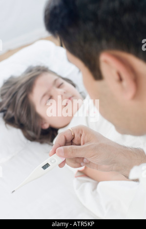 Close-up of a mid adult man checking temperature of his daughter Stock Photo