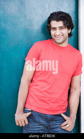 Portrait of a young man leaning against a door and smiling Stock Photo