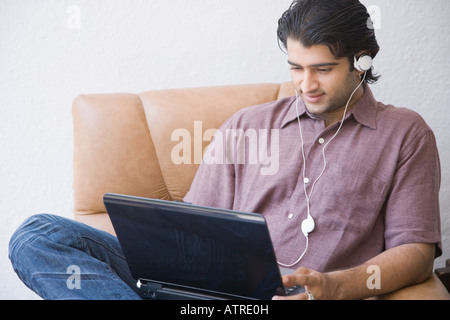 Young man sitting in an armchair and using a laptop Stock Photo