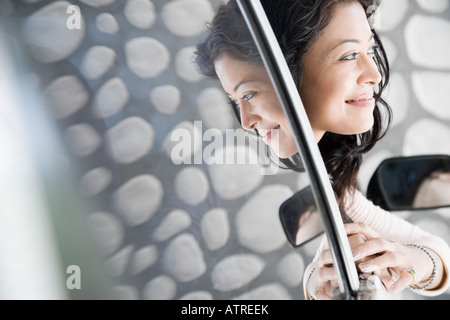 Close-up of a young woman peeking through a car window Stock Photo