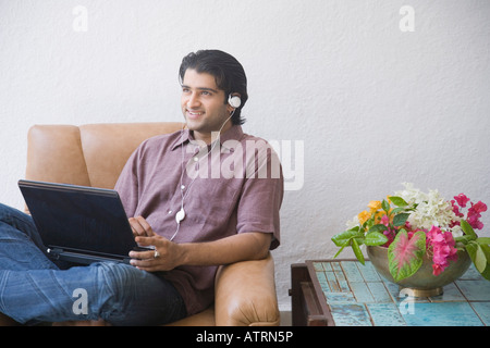 Young man sitting in an armchair and using a laptop Stock Photo