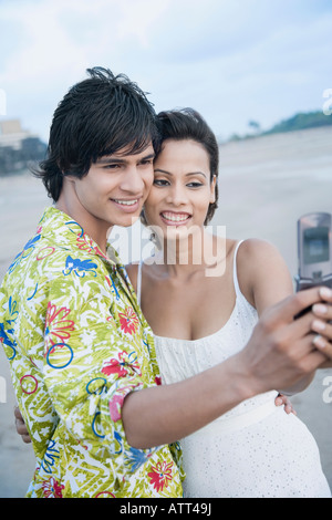 Side profile of a young couple taking a photograph of themselves with a mobile phone Stock Photo