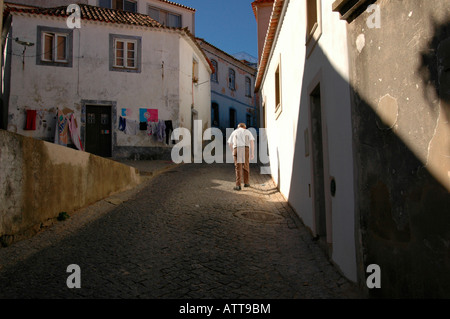 An elderly man walking in the cobbled street leading uphill toward Convento Nossa Senhora De Desterro monastery in Monchique town in Algarve Portugal Stock Photo