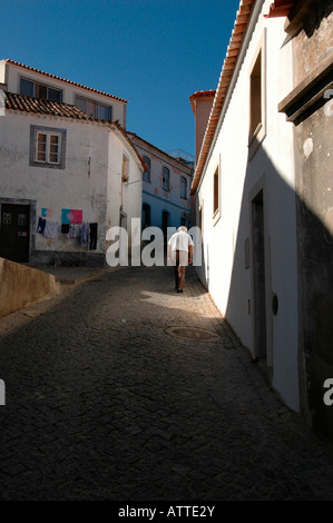 An elderly man walking in the cobbled street leading uphill toward Convento Nossa Senhora De Desterro monastery in Monchique town in Algarve Portugal Stock Photo