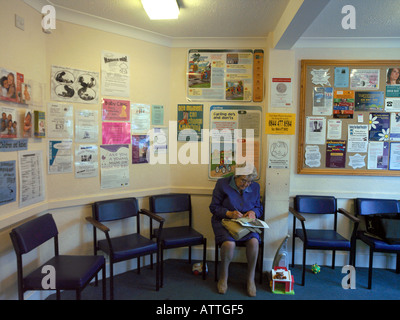 Doctors Surgery Waiting Room with Patient and Notices Cycling Safety Notice and Baby Clinic Notice in Cheam Surrey England Stock Photo