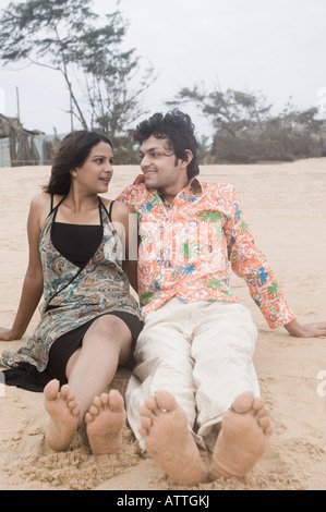 Young couple sitting on the beach and smiling Stock Photo