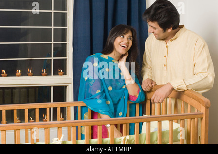 Young woman and a mid adult man standing near a crib and smiling Stock Photo