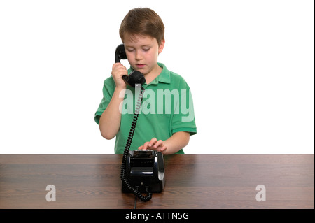 Young boy dialling a number on a retro telephone white background Stock Photo