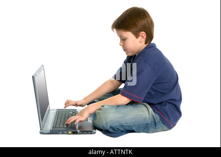 Young boy working on a laptop computer white background with slight shadow Stock Photo