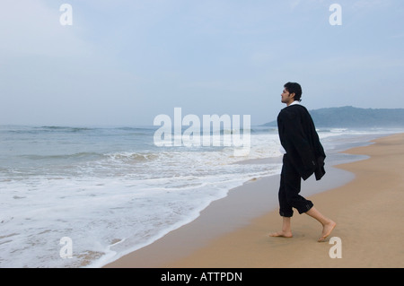 Side profile of a businessman walking on the beach Stock Photo