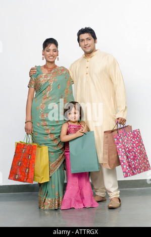 Mid adult man and a young woman with their daughter standing with shopping bags Stock Photo