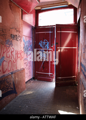 half open red door leading from hallway to the outdoors walls covered with graffiti Stock Photo