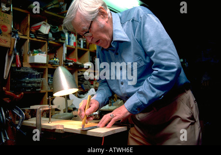 Retired physician age 85 marking board for cutting in his workshop. Minneapolis Minnesota USA Stock Photo