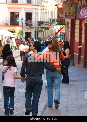 MEXICO Guanajuato Mexican man and woman holding hands with daughter walking down busy street in city pedestrian thoroughfare Stock Photo