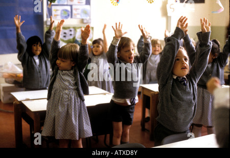 Nursery age children in South London preparatory school standing with arms stretching high Stock Photo