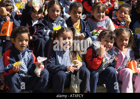 MEXICO Guanajuato Group of young Mexican school children sitting together on steps gingham check smocks boys and girls smiling Stock Photo