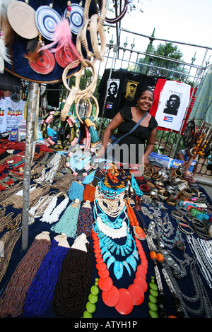 Stall lady shows off bright colour costume jewellery, masks, in street market, Ipanema, Rio de Janeiro, Brazil, South America Stock Photo
