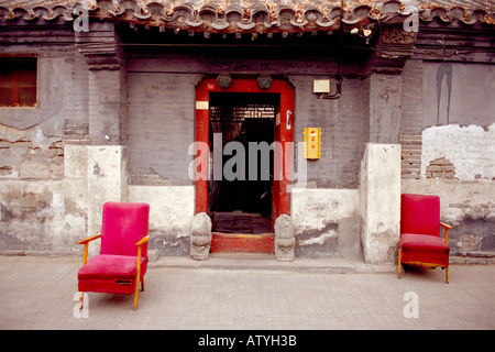 Two old red velvet chairs outside the door of a typical house in the hutong of Beijing China. Stock Photo