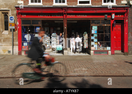 Cambridge university town Trinity Street Post Office store cyclist hurtles past Stock Photo