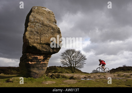 Mountain biker riding past the Cork Stone, Stanton Moor, Peak District, Derbyshire Stock Photo