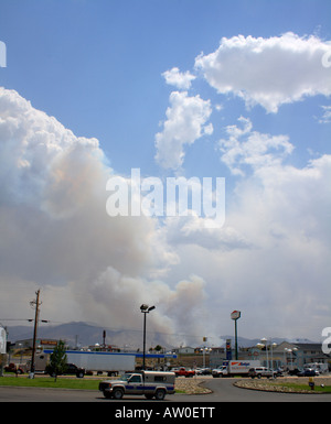 Smoke rises from a nearby hillside range fire as vehicle traffic moves in front of it. Stock Photo