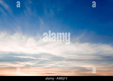 Horizontal wide angle of a deep blue sky at sunset with various cloud formations turning pink on the horizon Stock Photo