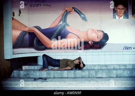 South East Asia, Thailand, Bangkok, homeless man sleeping under bill board poster Stock Photo