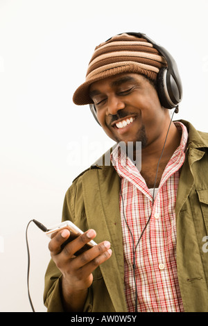 African American mid adult man wearing knit hat and listening to headphones and mp3 player Stock Photo