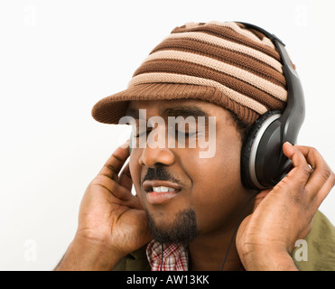 African American mid adult man wearing knit hat and listening to headphones with eyes closed Stock Photo