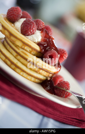 Stack of delicious american small pancakes topped with jelly and raspberries Stock Photo