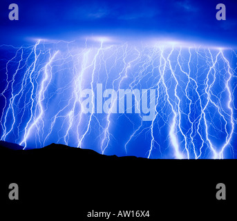 Multiple lightning bolts layer the sky at night over a desert mountain ...