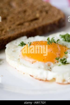 Fried egg with whole eggyolk and sandwich in background Stock Photo
