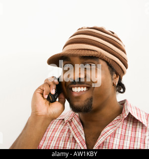 African American mid adult man wearing hat and smiling while talking on cell phone Stock Photo