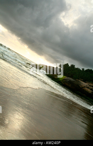 Dark clouds looming over a beach just before sunset in Kerala conveys a moody feel Stock Photo