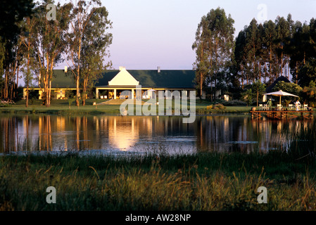 Zimbabwean farmhouse at sunset, viewed across a dam Stock Photo