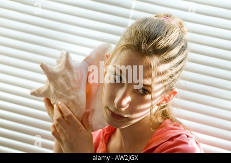 indoor portrait of young girl holding large sea shell Stock Photo