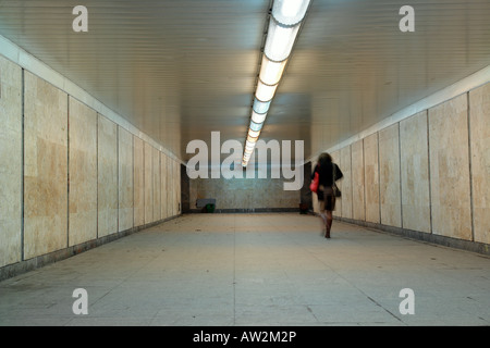 Woman with red bag going through underground passage Stock Photo