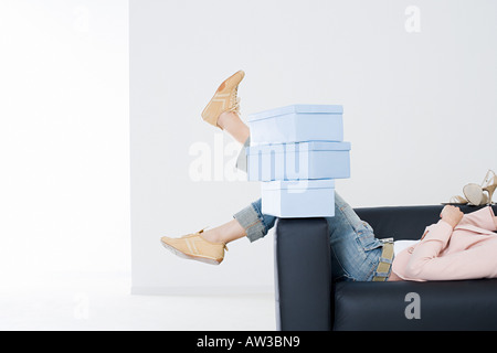 Woman on sofa with shoe boxes Stock Photo
