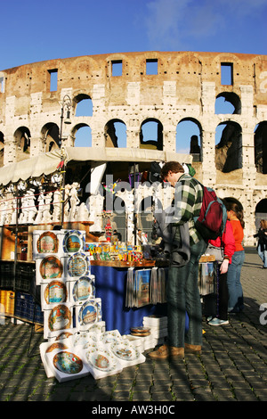 Tourists browse the keepsake mementos on a souvenir stall in front of the famous monument the Colosseum, Rome Italy Europe EU Stock Photo