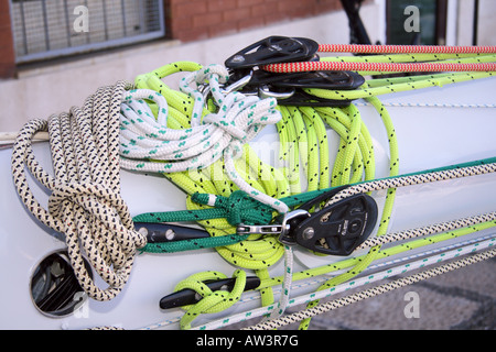 Colourful coiled sailing ropes - lime-green, white and red halyards and sheets - with pulley blocks on the white deck of a sailing yacht in Cagliari, Sardinia, Italy. Stock Photo