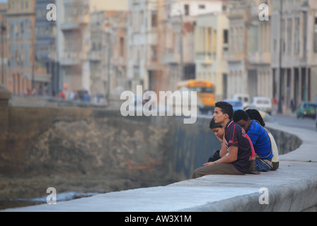 Young people sitting on a wall Malecón Havana Habana Cuba Caribbean Stock Photo