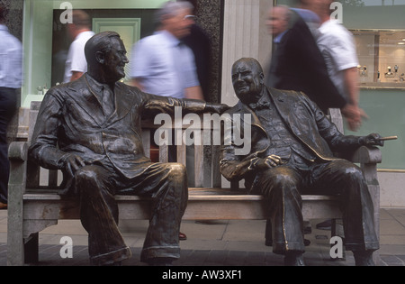 Bronze sculptures of FD Roosevelt and Winston Churchill on bench amid swirl of passing businessmen, New Bond Street, London Stock Photo