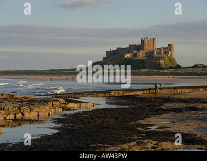 Bamburgh Castle sea waves beach rocks reflections from Bamburgh beach Northumberland Northern England uk Stock Photo