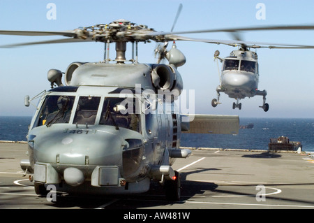 Nato cooperation a US Navy Seahawk helicopter on the deck of the UK HMS Albion while a French Navy Lynx helicopter landing Stock Photo