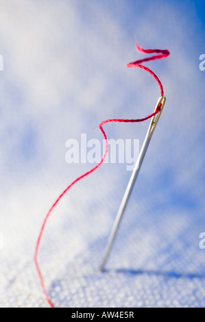 red thread through needle hole. Close-up Stock Photo