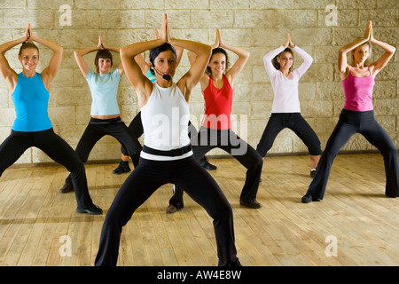 A group of women exercising with fitness instructor in the gym Focus on the woman in white shirt Front view Stock Photo