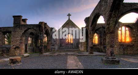 Interior of a burnt out church attacked by arsonists and left as a ruin with a blazing sunrise through the glassless windows Stock Photo