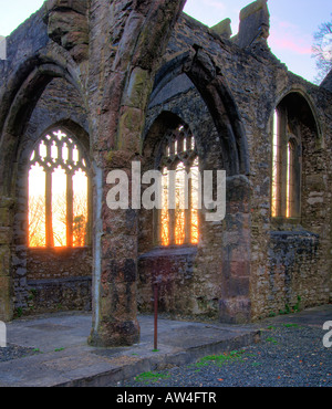 Interior of a burnt out church attacked by arsonists and left as a ruin with a blazing sunrise through the glassless windows Stock Photo