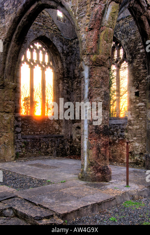 Interior of a burnt out church attacked by arsonists and left as a ruin with a blazing sunrise through the glassless windows Stock Photo