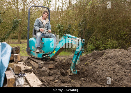 a man driving a mini digger / excavator Stock Photo